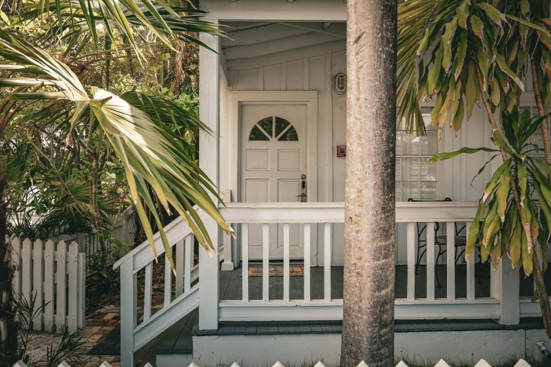 Charming tropical front porch with palm trees and white wood