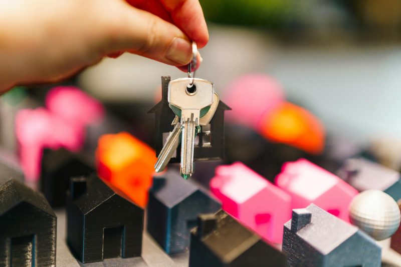 Colorful miniature houses and a hand holding keys